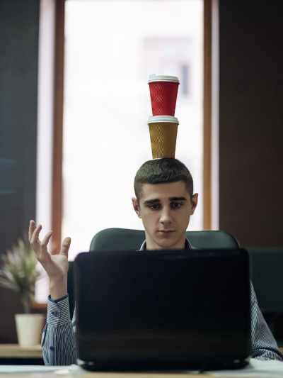 man balancing coffee cups on his head while working at laptop man balancing coffee cups on his head while working at laptop