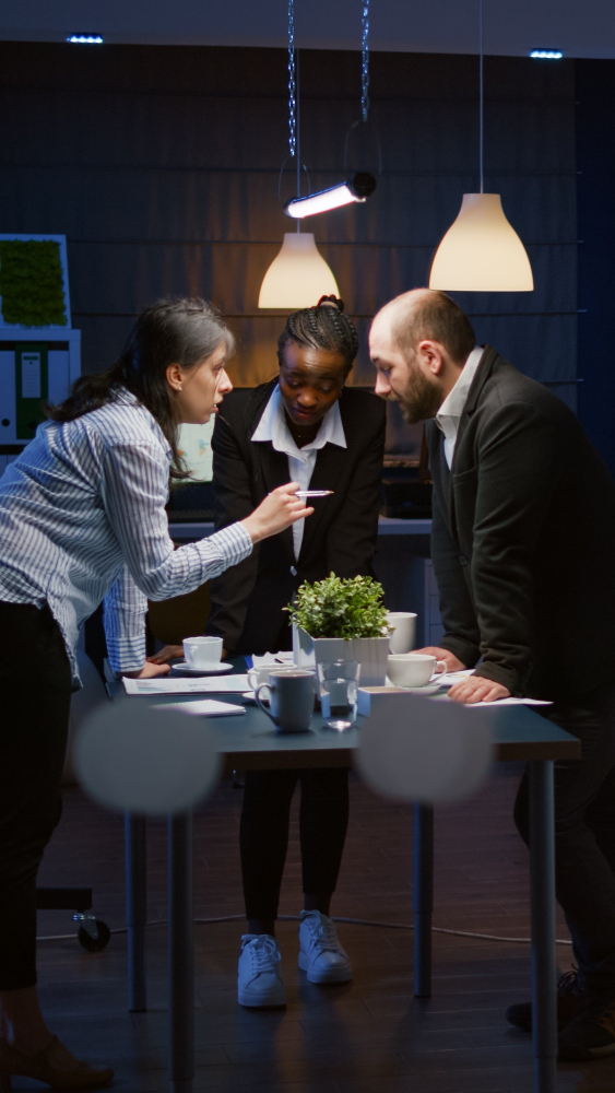 three people standing at table with reports three people standing at table with reports