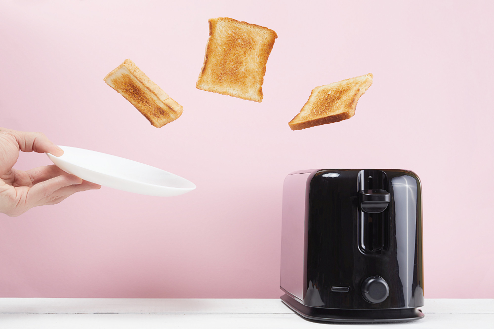 Toast jumping out of a toaster onto a plate being held to the side Toast jumping out of a toaster onto a plate being held to the side