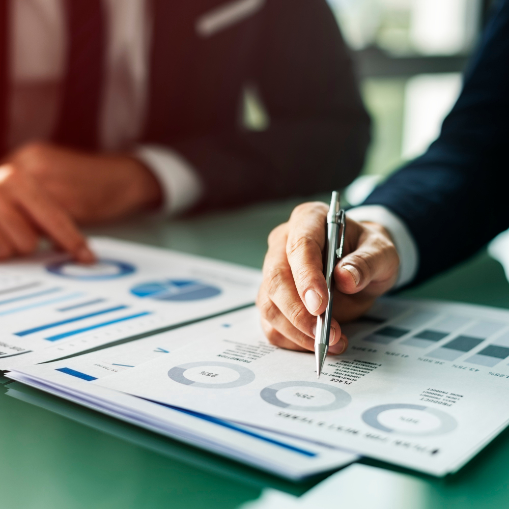 business reports with two people looking at them (you can only see their hands and arms) business reports with two people looking at them (you can only see their hands and arms)