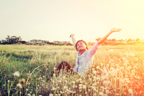 a happy woman of colour enjoying a field of flowers on a sunny day a happy woman of colour enjoying a field of flowers on a sunny day